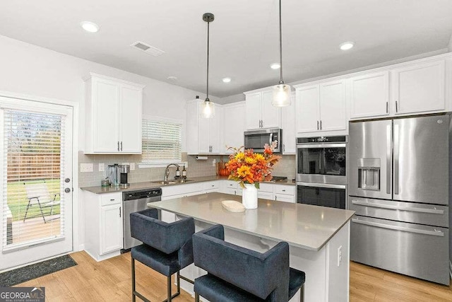 kitchen featuring appliances with stainless steel finishes, a center island, hanging light fixtures, and a healthy amount of sunlight