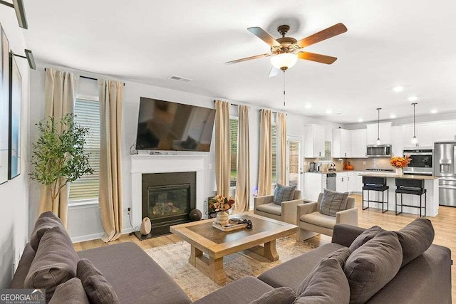 living room featuring light wood-type flooring and ceiling fan