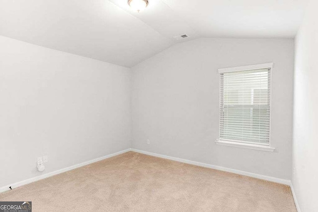 carpeted spare room with vaulted ceiling