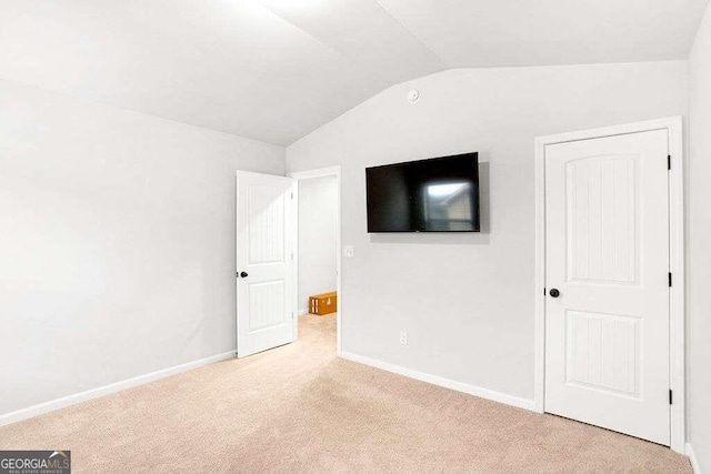 unfurnished bedroom featuring lofted ceiling and light carpet