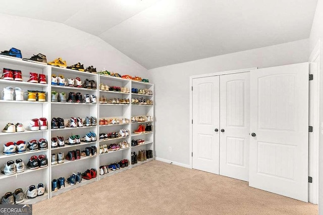 walk in closet with light colored carpet and lofted ceiling