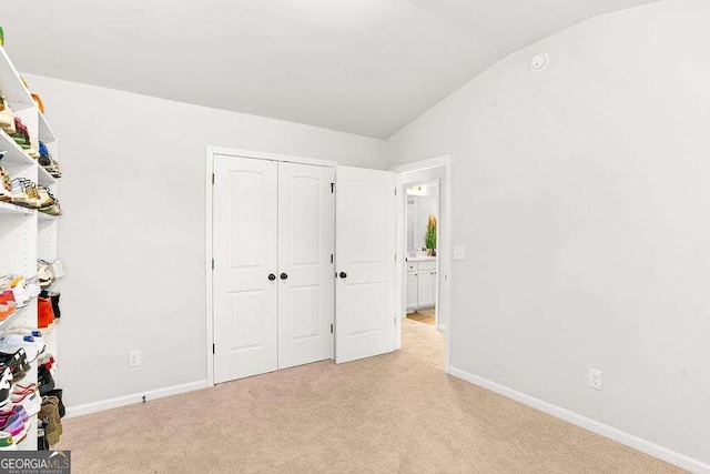 unfurnished bedroom featuring light carpet and vaulted ceiling