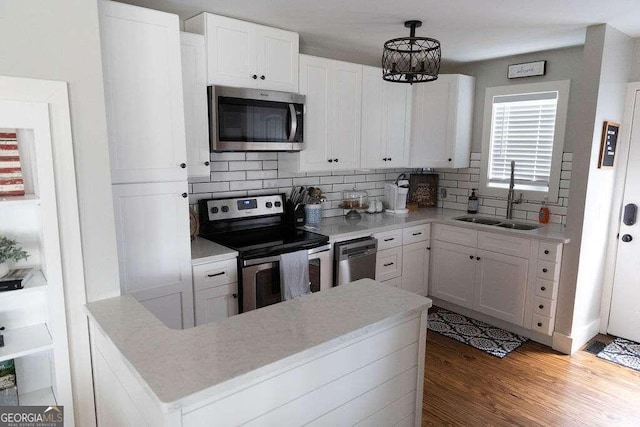 kitchen featuring appliances with stainless steel finishes, white cabinetry, dark hardwood / wood-style flooring, backsplash, and hanging light fixtures