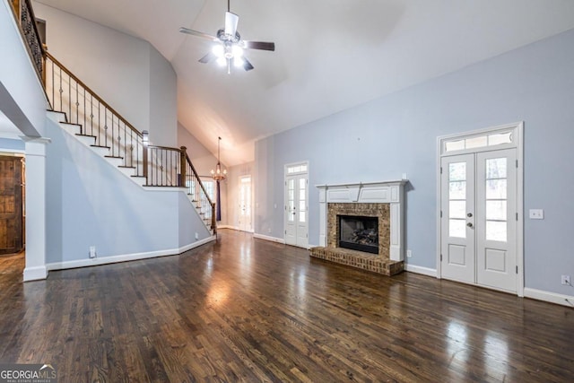 unfurnished living room featuring a brick fireplace, dark wood-type flooring, high vaulted ceiling, and french doors