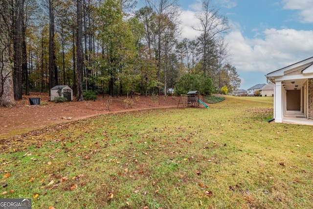 view of yard with a storage shed and a playground