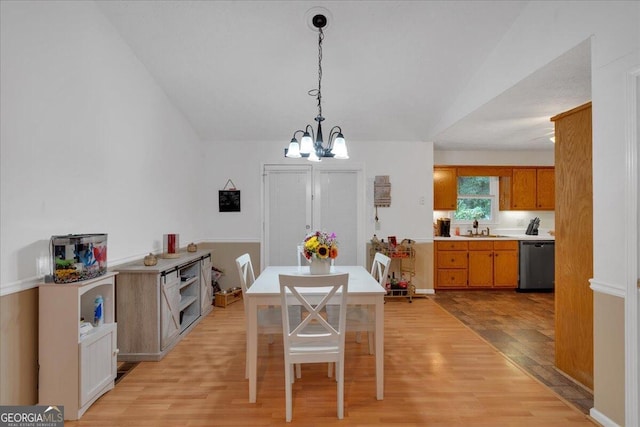 dining room with sink, light hardwood / wood-style floors, lofted ceiling, and a notable chandelier