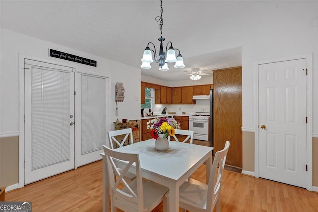 dining space featuring ceiling fan with notable chandelier, light hardwood / wood-style floors, and sink