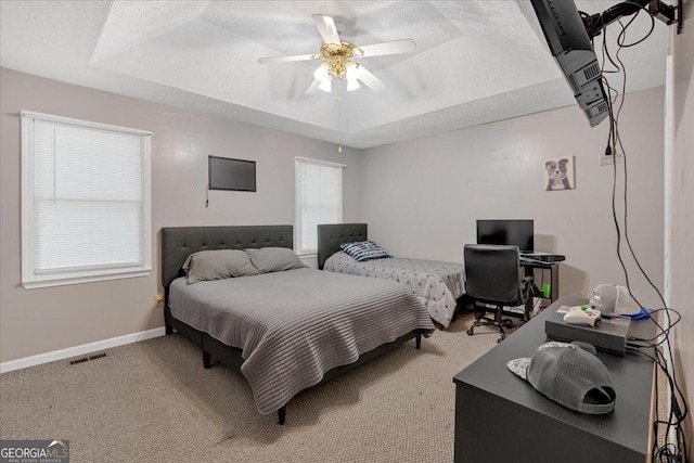 carpeted bedroom with ceiling fan, a raised ceiling, and a textured ceiling