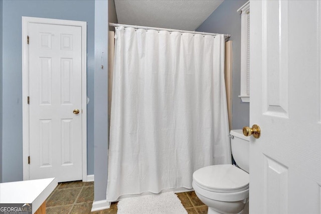 bathroom with tile patterned flooring, a textured ceiling, and toilet