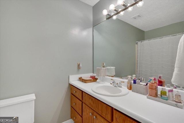 bathroom with vanity, toilet, and a textured ceiling