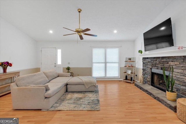 living room featuring a fireplace, ceiling fan, and light hardwood / wood-style flooring