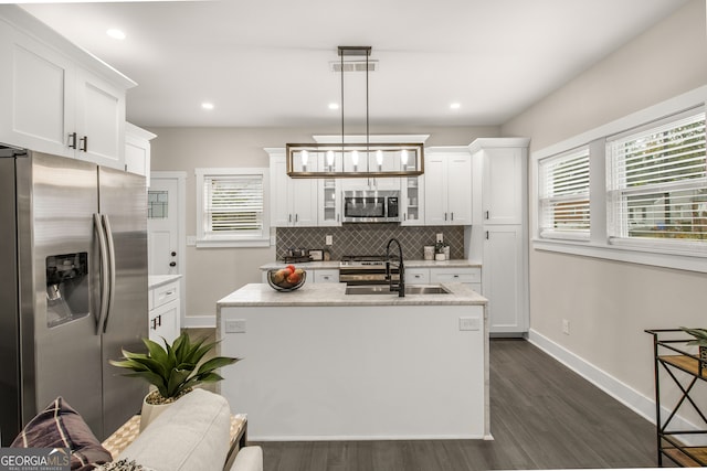 kitchen with sink, stainless steel appliances, dark hardwood / wood-style flooring, an island with sink, and pendant lighting