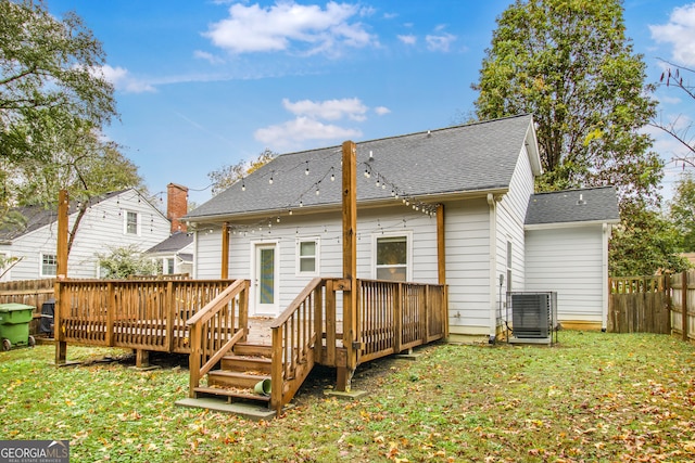 back of property featuring central AC unit, a wooden deck, and a lawn