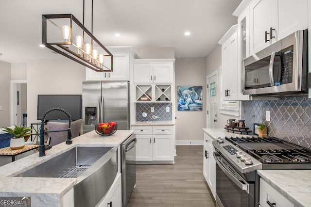 kitchen featuring white cabinets, appliances with stainless steel finishes, light hardwood / wood-style flooring, and pendant lighting