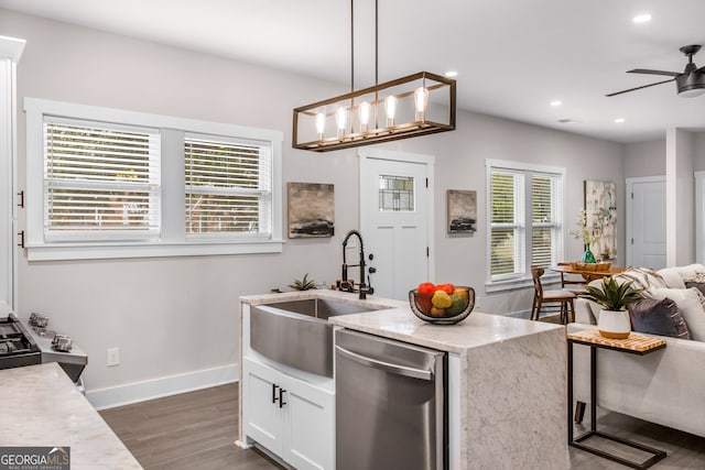 kitchen featuring plenty of natural light, white cabinets, stainless steel dishwasher, and decorative light fixtures