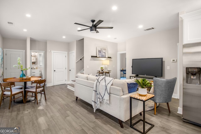 living room with light hardwood / wood-style floors and ceiling fan