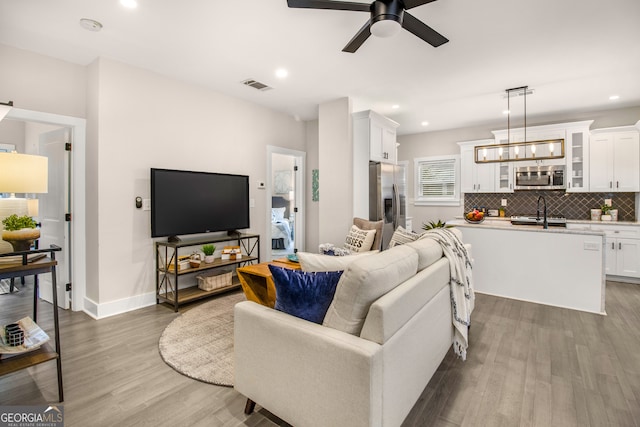 living room with hardwood / wood-style flooring and ceiling fan with notable chandelier