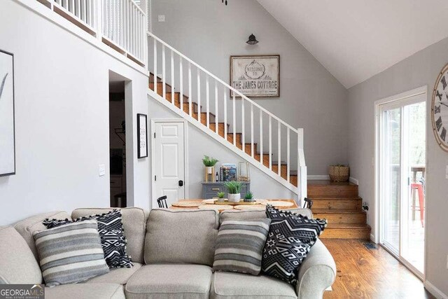 living room featuring wood-type flooring and high vaulted ceiling