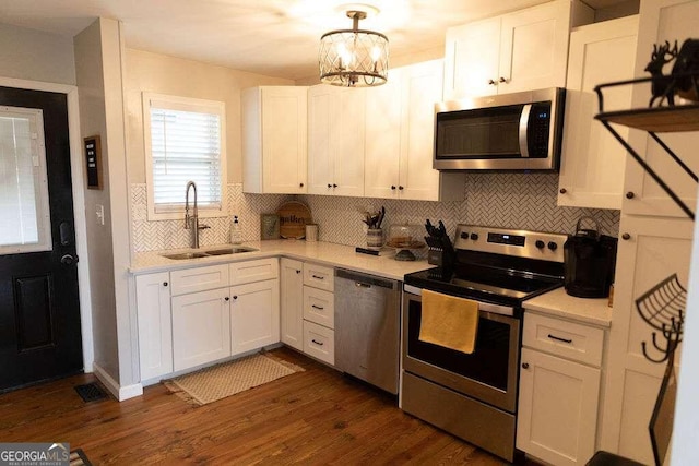 kitchen featuring appliances with stainless steel finishes, white cabinetry, sink, backsplash, and hanging light fixtures