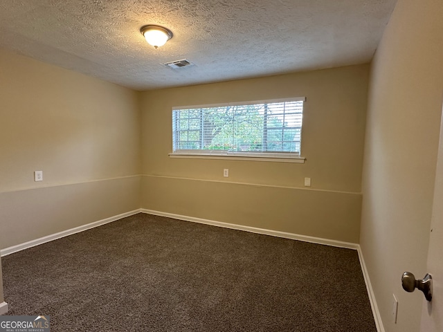 carpeted empty room featuring a textured ceiling