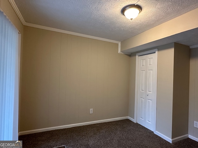 interior space with dark colored carpet, ornamental molding, a textured ceiling, and a closet