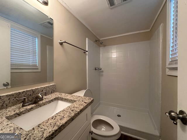 bathroom featuring a tile shower, vanity, and toilet