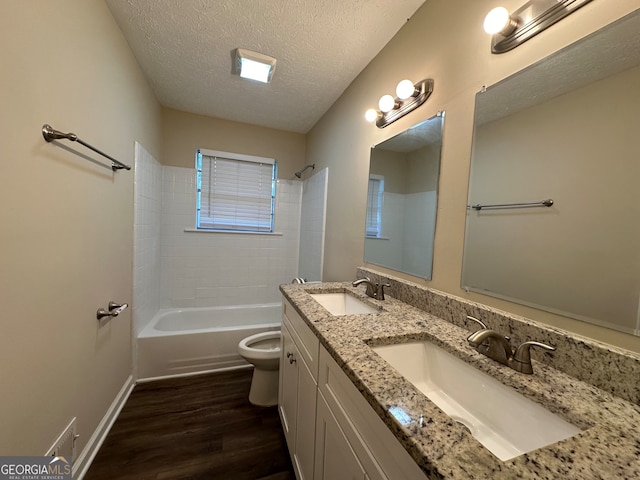 full bathroom with a textured ceiling, toilet, hardwood / wood-style flooring, vanity, and tiled shower / bath