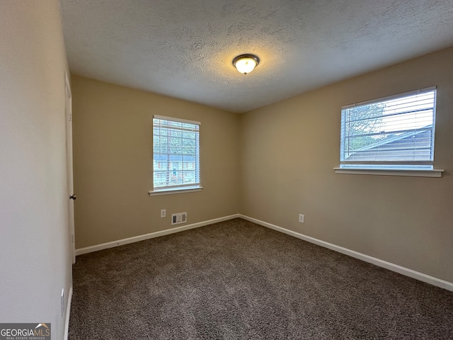 carpeted empty room with a textured ceiling