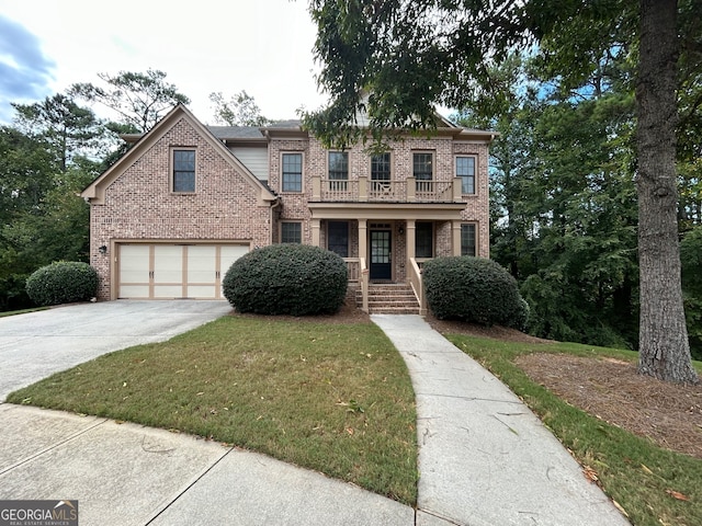 view of front of house featuring a garage, a balcony, and a front lawn