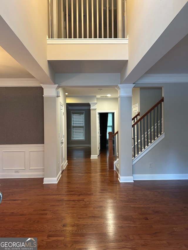 foyer featuring dark hardwood / wood-style floors, a towering ceiling, and ornamental molding