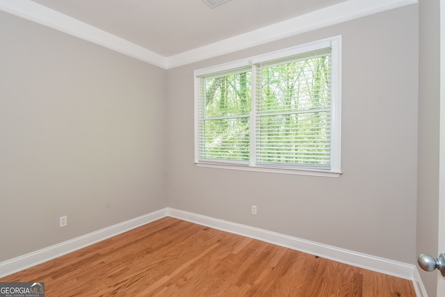 unfurnished room featuring plenty of natural light, wood-type flooring, and ornamental molding