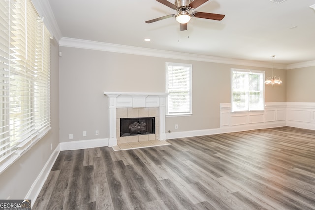 unfurnished living room featuring hardwood / wood-style floors, ceiling fan with notable chandelier, crown molding, and a tiled fireplace