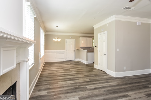 unfurnished living room with ceiling fan with notable chandelier, ornamental molding, and dark wood-type flooring