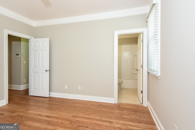 unfurnished bedroom with ensuite bath, ceiling fan, ornamental molding, and light wood-type flooring