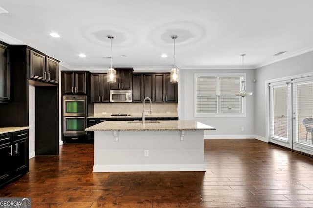 kitchen featuring a center island with sink, light stone countertops, sink, and appliances with stainless steel finishes