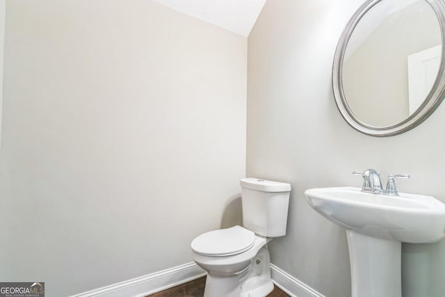 bathroom with toilet, sink, and vaulted ceiling