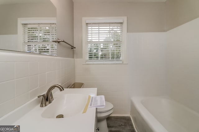 bathroom with vanity, toilet, a tub, and tile walls