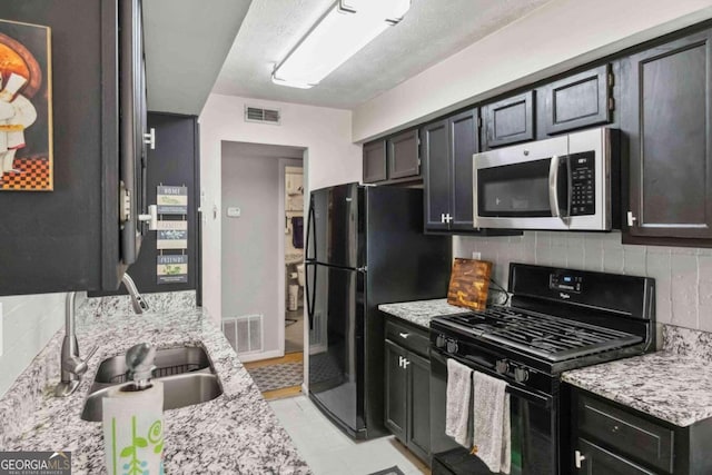 kitchen with sink, backsplash, light stone countertops, and black appliances