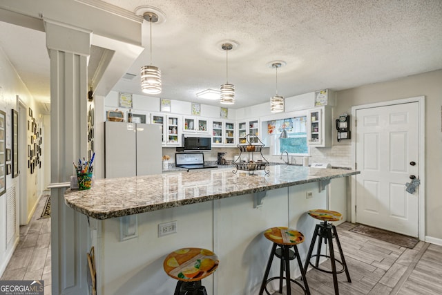 kitchen with white cabinets, light hardwood / wood-style floors, light stone counters, and black appliances