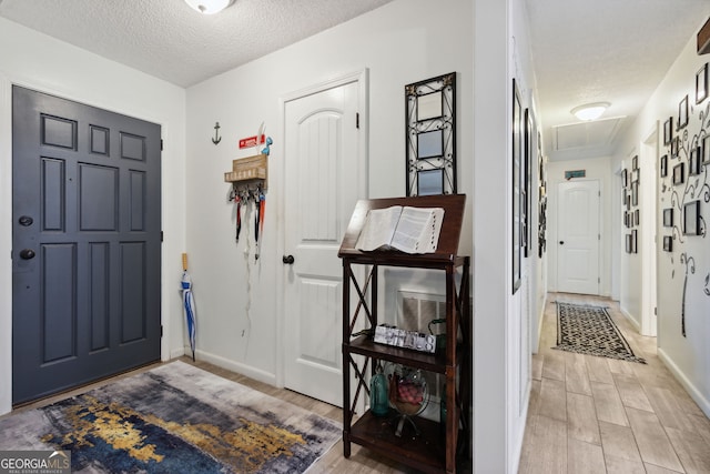 foyer entrance featuring a textured ceiling and light wood-type flooring