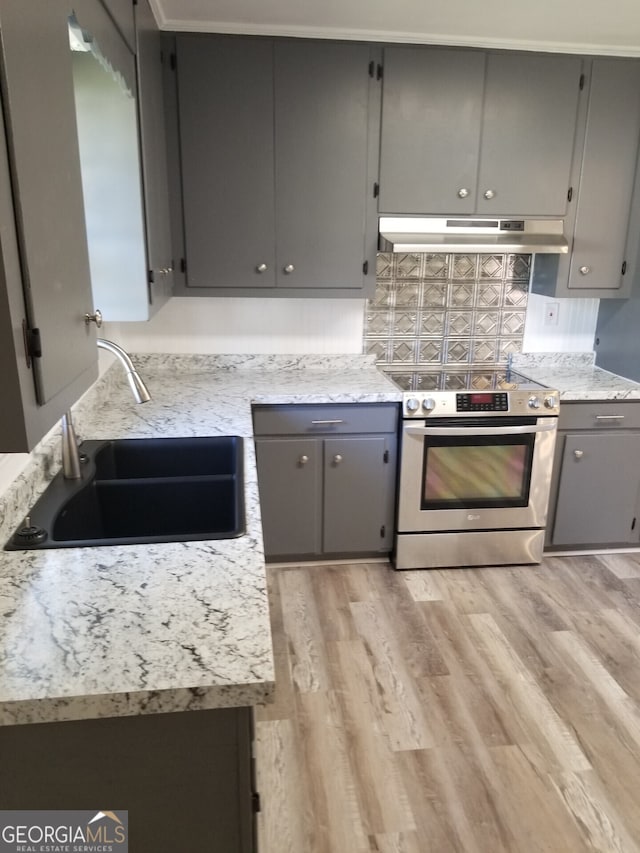 kitchen featuring gray cabinetry, sink, tasteful backsplash, stainless steel range oven, and light wood-type flooring