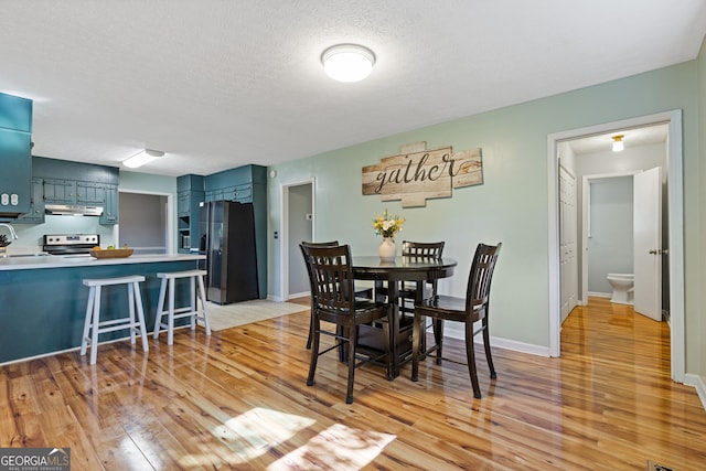 dining area with a textured ceiling, light hardwood / wood-style floors, and sink