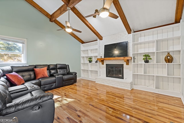 living room featuring ceiling fan, a fireplace, lofted ceiling with beams, and hardwood / wood-style flooring