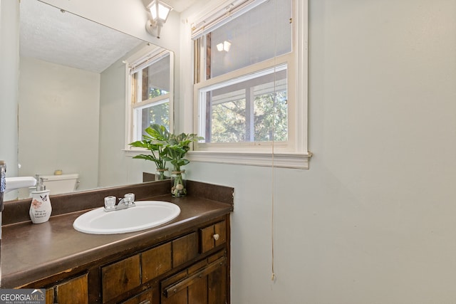 bathroom featuring vanity, a textured ceiling, and toilet