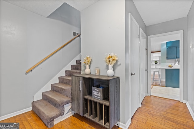 stairway featuring a textured ceiling and hardwood / wood-style flooring