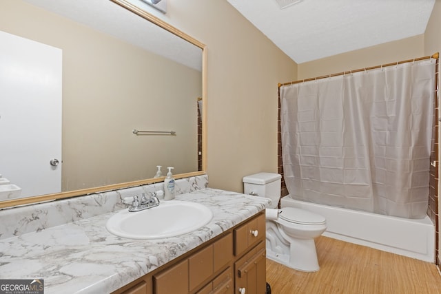 full bathroom featuring vanity, hardwood / wood-style flooring, toilet, shower / bathtub combination with curtain, and a textured ceiling