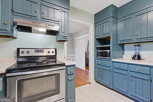 kitchen with appliances with stainless steel finishes, light wood-type flooring, a textured ceiling, and blue cabinets