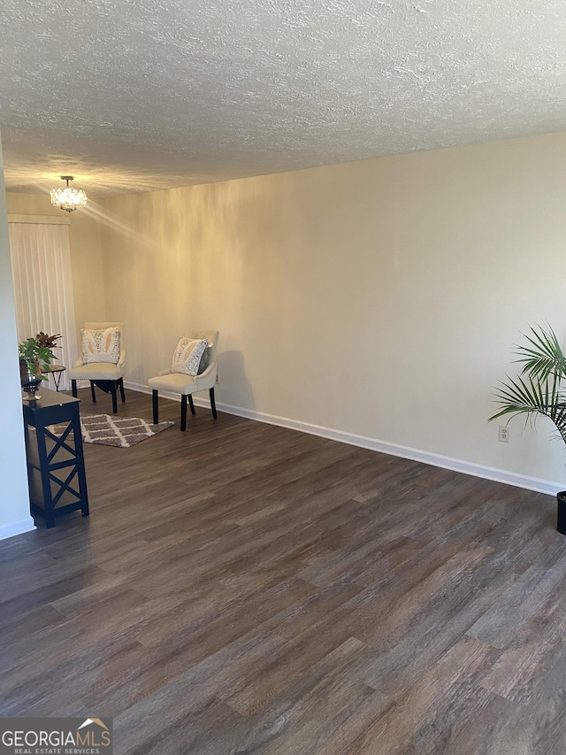 living area featuring a textured ceiling, dark wood-type flooring, and a notable chandelier