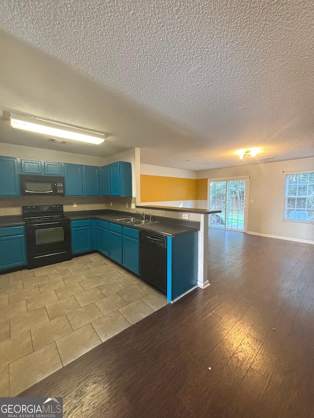 kitchen with sink, blue cabinets, kitchen peninsula, black appliances, and light wood-type flooring