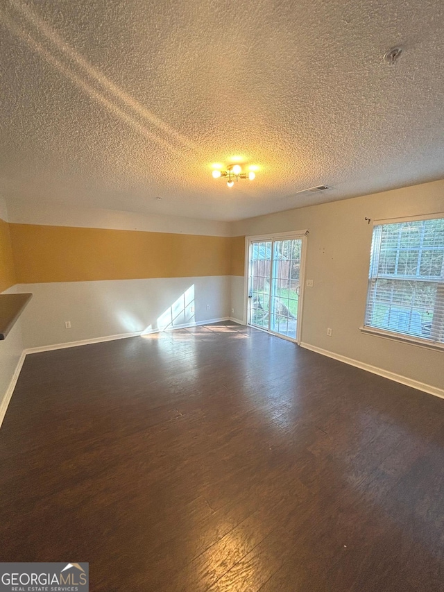 unfurnished room with a textured ceiling and dark hardwood / wood-style floors